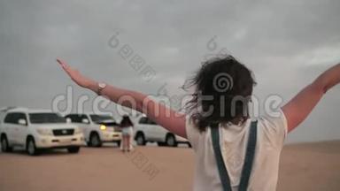 在阿拉伯联合酋长国，一辆沙漠旅游观光车的背景上摆着一个快乐的女孩。